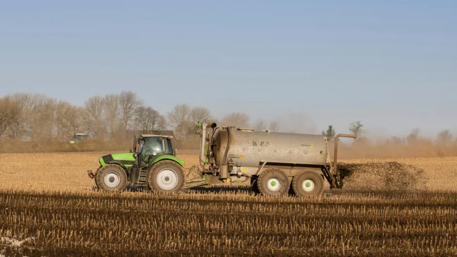 Das Bild zeigt einen Traktor beim Düngen eines Feldes. 